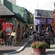 Quaint buildings line an outdoor patio and guests sit at tables eating